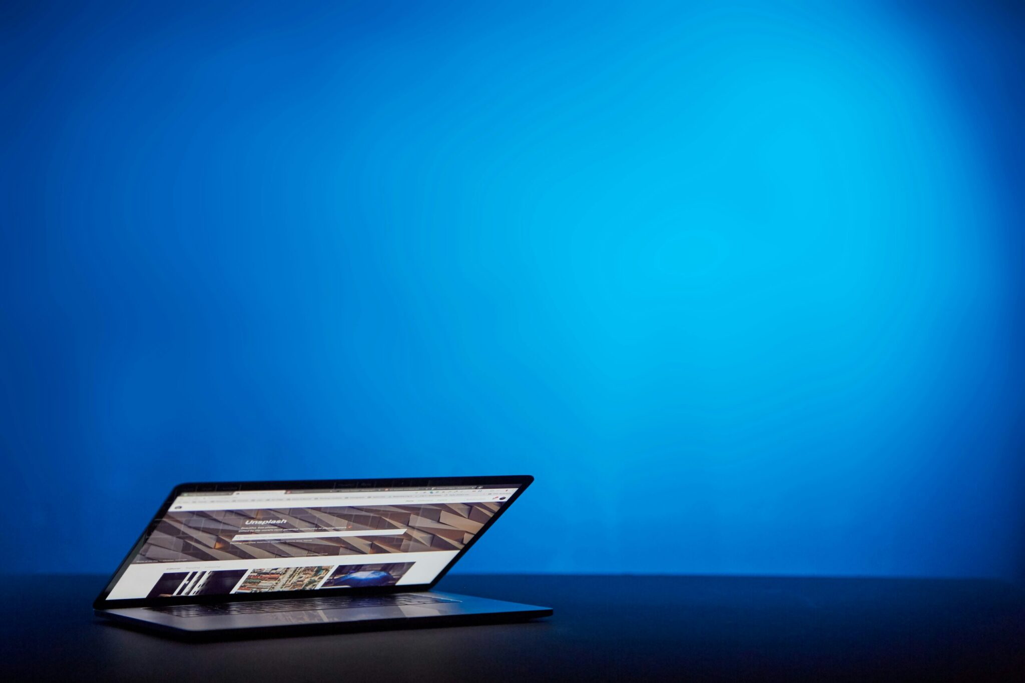 A partially open laptop sits on a dark surface against a plain, bright blue background, ready for buyers to browse site visit reports or explore brand opinions.