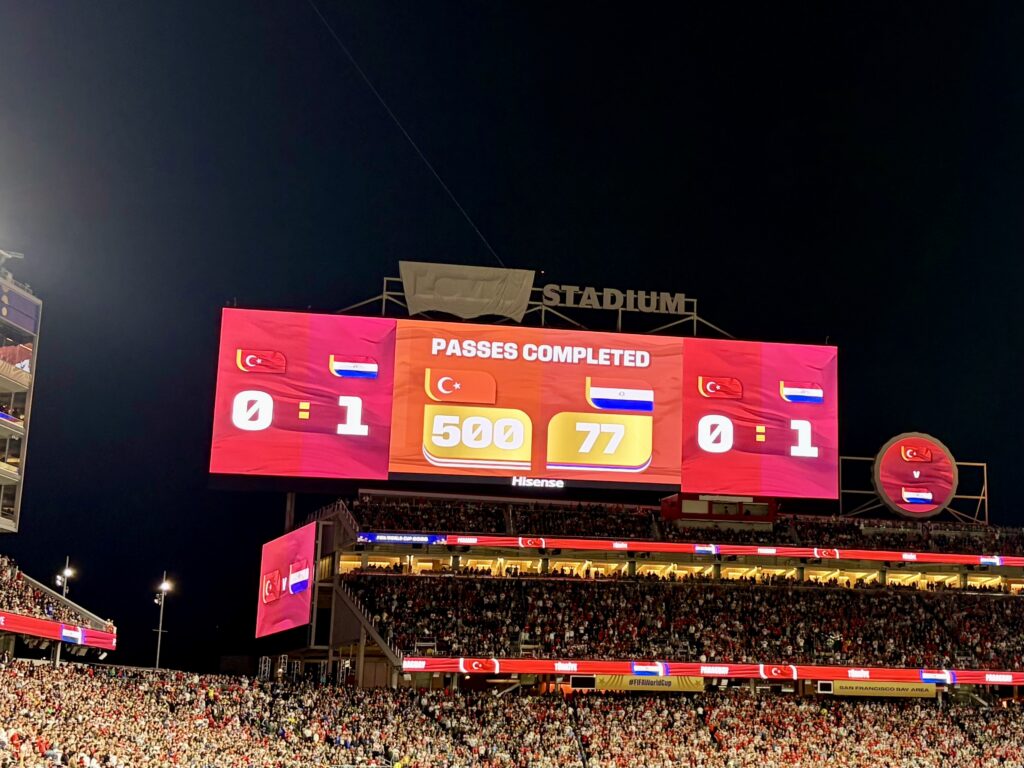Scoreboard at a stadium shows Turkey 0-1 Russia, with Russia completing 500 passes to Turkey's 77.