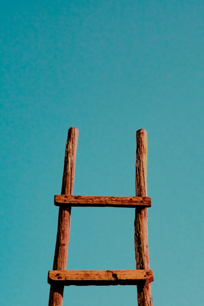 A rustic wooden ladder against a clear blue sky.