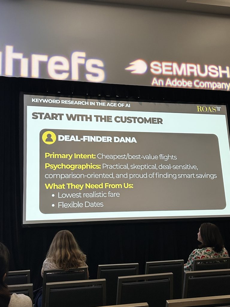 Presentation slide on “Deal-Finder Dana,” discussing customer intent and needs, viewed by attendees in a conference room.