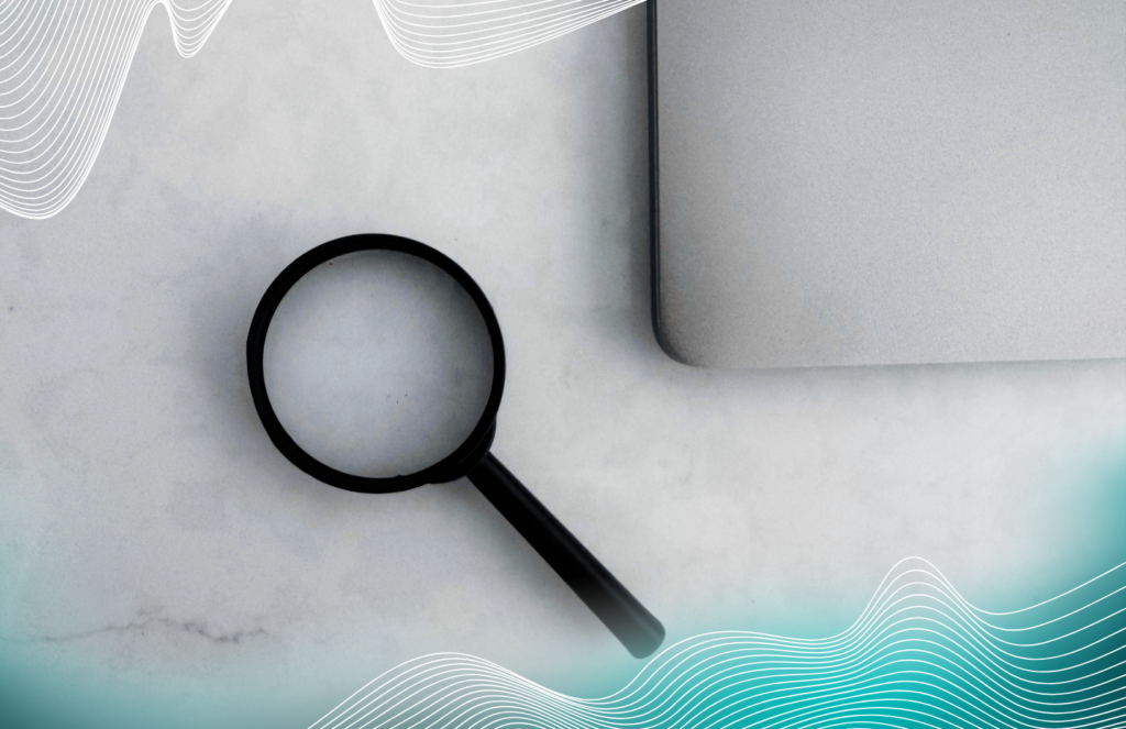 A magnifying glass next to a laptop on a white desk with wavy line graphics in the corners.